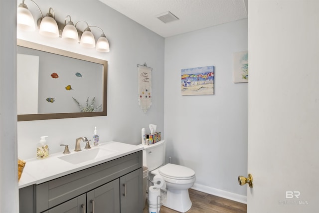 bathroom with visible vents, toilet, wood finished floors, a textured ceiling, and vanity