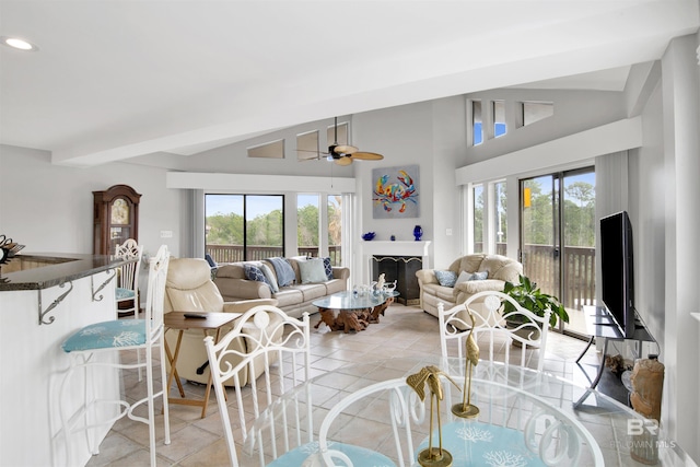 living area featuring ceiling fan, a fireplace, high vaulted ceiling, and light tile patterned floors