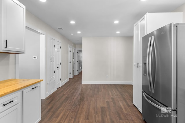 kitchen with stainless steel refrigerator with ice dispenser, dark hardwood / wood-style floors, white cabinetry, and wooden counters