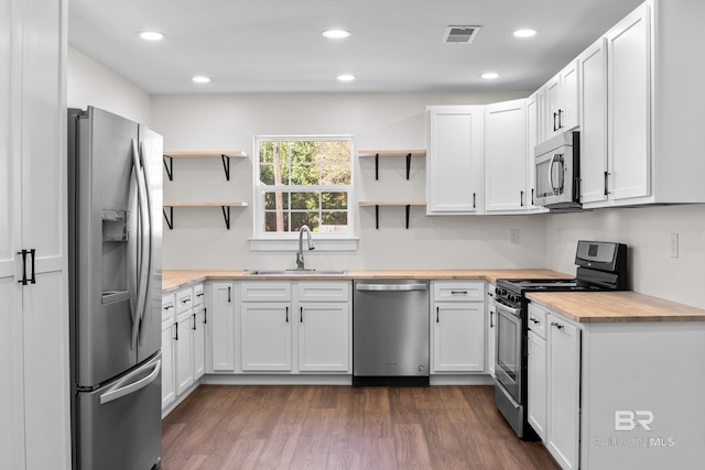 kitchen featuring appliances with stainless steel finishes, white cabinets, dark hardwood / wood-style flooring, butcher block counters, and sink