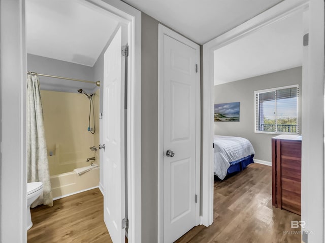 bathroom featuring toilet, shower / tub combo with curtain, and hardwood / wood-style flooring