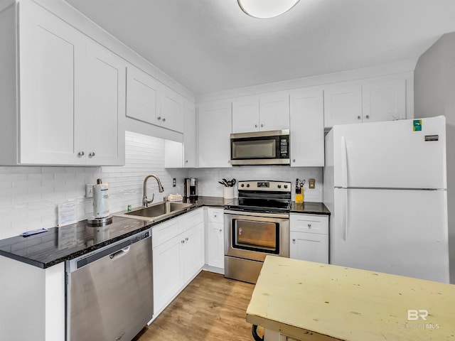 kitchen with white cabinetry, sink, light hardwood / wood-style flooring, backsplash, and appliances with stainless steel finishes