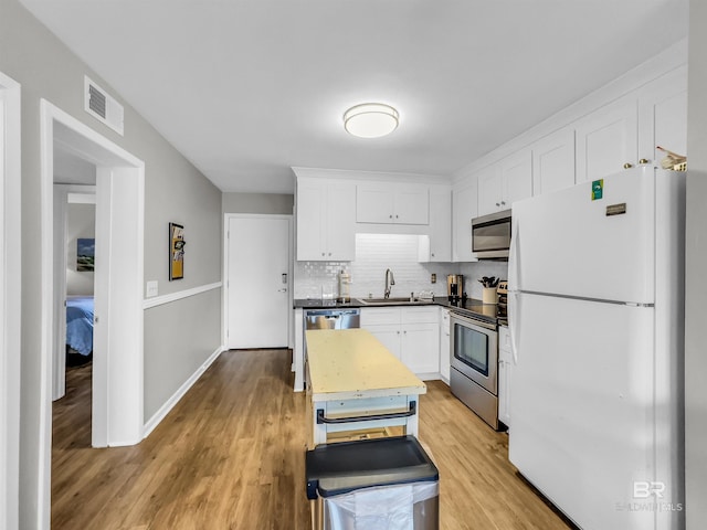 kitchen featuring white cabinets, stainless steel appliances, light hardwood / wood-style flooring, and sink