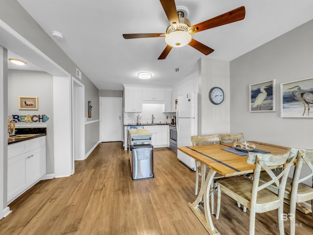 kitchen featuring light hardwood / wood-style floors, decorative backsplash, white refrigerator, and white cabinetry