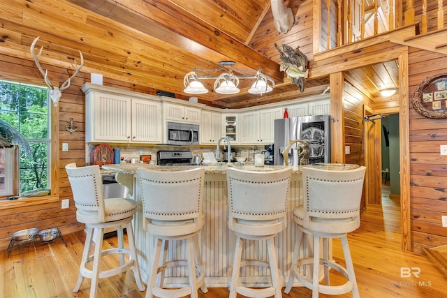 42168 Bayou Rd, Bay Minette, AL 36507 - kitchen featuring stainless steel appliances, wooden walls, light wood finished floors, glass insert cabinets, and a breakfast bar area