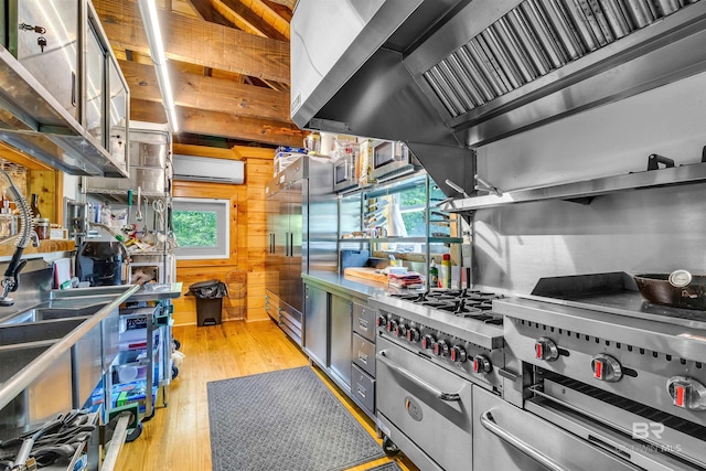 42168 Bayou Rd, Bay Minette, AL 36507 - kitchen featuring an AC wall unit, wood walls, healthy amount of natural light, wall chimney exhaust hood, and light wood-type flooring