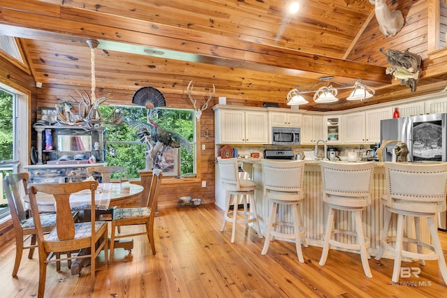 42168 Bayou Rd, Bay Minette, AL 36507 - kitchen featuring stainless steel appliances, wooden ceiling, light wood-type flooring, glass insert cabinets, and a kitchen breakfast bar