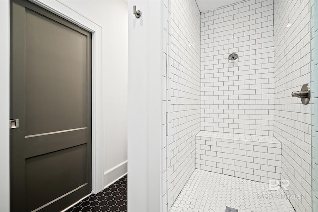 bathroom with a tile shower and tile patterned flooring