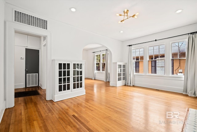 unfurnished living room with an inviting chandelier and light wood-type flooring