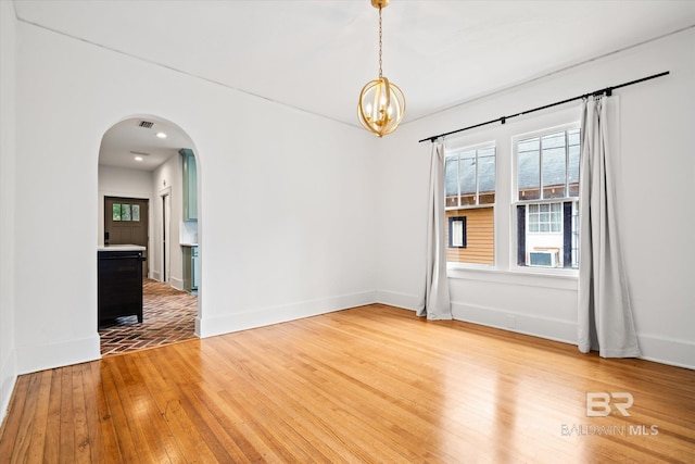 spare room featuring an inviting chandelier and light wood-type flooring