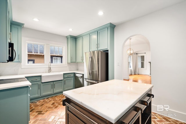 kitchen featuring green cabinets, backsplash, a center island, sink, and appliances with stainless steel finishes