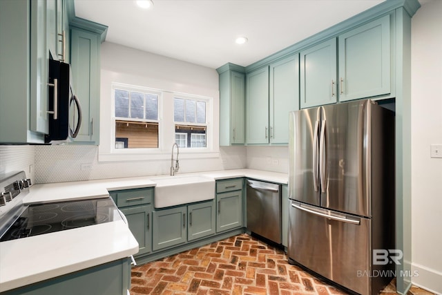 kitchen with green cabinetry, appliances with stainless steel finishes, backsplash, and sink