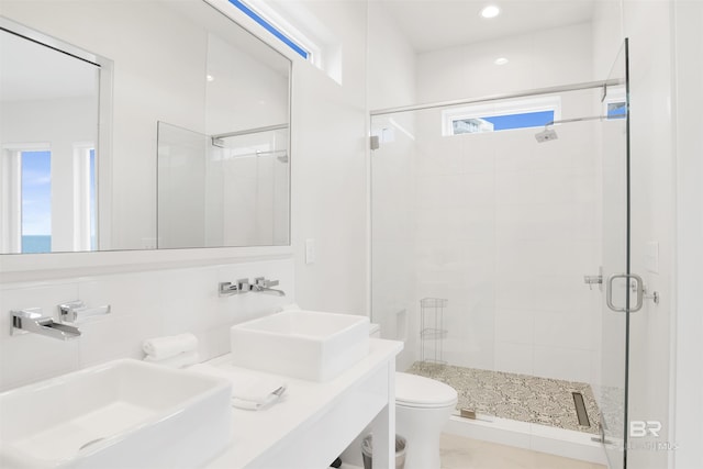bathroom with vanity, decorative backsplash, a shower with door, and toilet