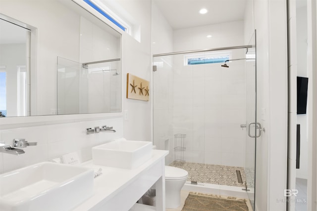 bathroom featuring toilet, a shower with door, and sink