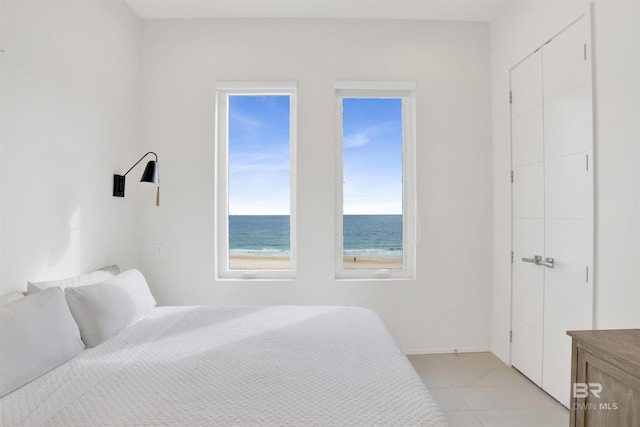 bedroom with light tile patterned floors and a water view