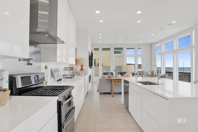 kitchen featuring appliances with stainless steel finishes, sink, white cabinets, exhaust hood, and a water view