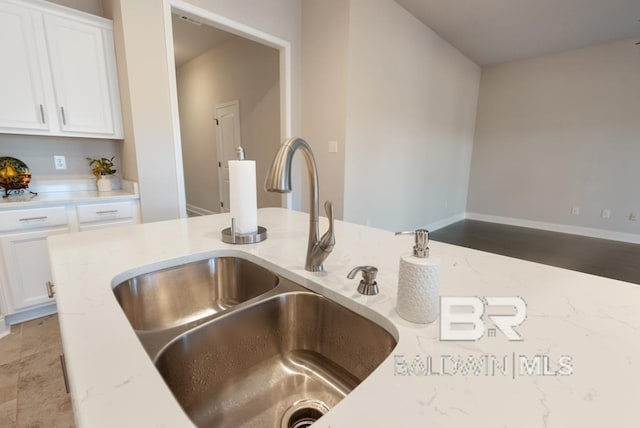 details featuring white cabinetry, sink, and light stone counters