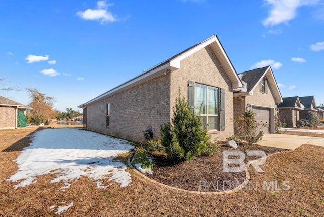 view of side of property featuring a garage, concrete driveway, and brick siding