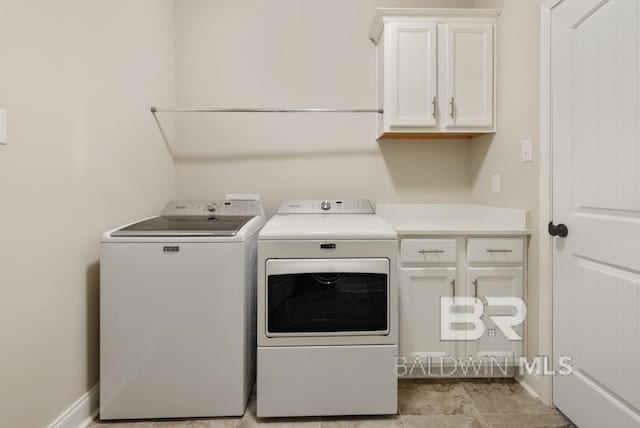 clothes washing area with cabinet space, washing machine and dryer, and baseboards