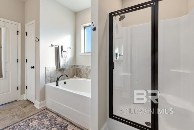 full bathroom with a garden tub, a shower stall, and baseboards