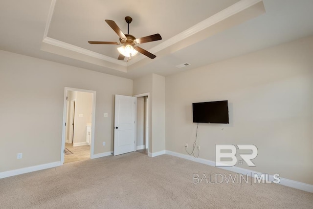 unfurnished bedroom featuring ceiling fan, ornamental molding, a tray ceiling, and light colored carpet