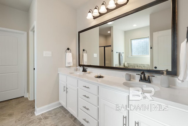 bathroom with double vanity, baseboards, a sink, and a shower with shower door