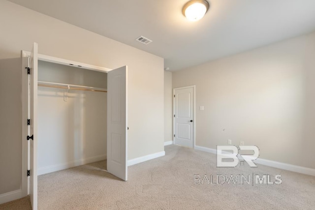 unfurnished bedroom featuring a closet, visible vents, light carpet, and baseboards