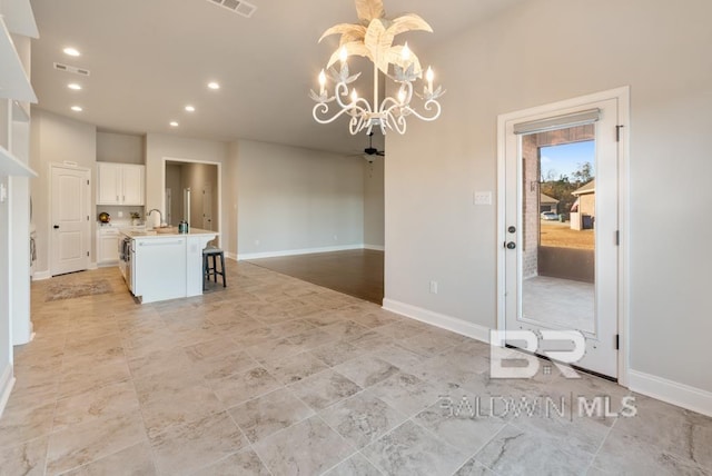 unfurnished dining area with sink and ceiling fan with notable chandelier