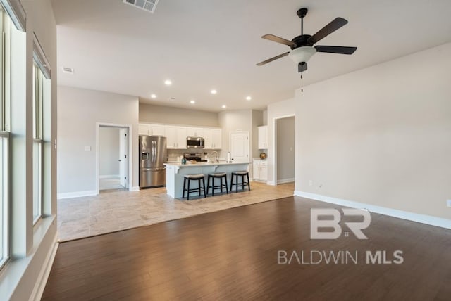 unfurnished living room featuring baseboards, light wood-type flooring, a ceiling fan, and recessed lighting