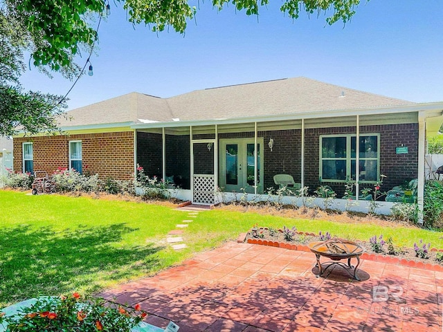 rear view of property with a lawn, a patio, and a fire pit