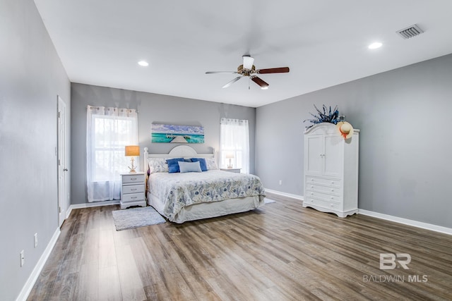 bedroom featuring ceiling fan, wood-type flooring, and multiple windows