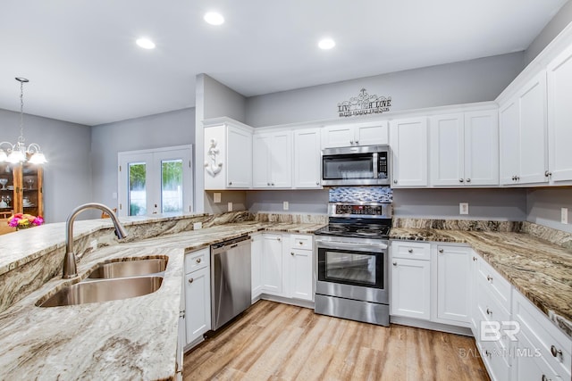 kitchen featuring white cabinets, decorative light fixtures, stainless steel appliances, and sink