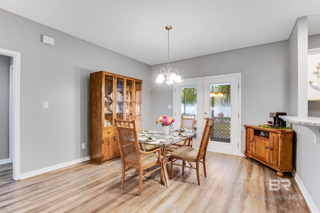 dining space featuring a chandelier, french doors, and light wood-type flooring