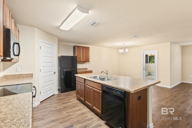 kitchen featuring sink, a notable chandelier, pendant lighting, a center island with sink, and black appliances