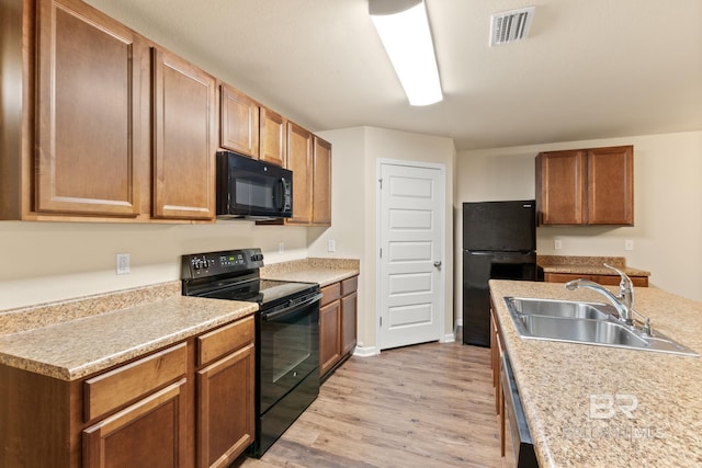 kitchen with sink, black appliances, and light hardwood / wood-style flooring