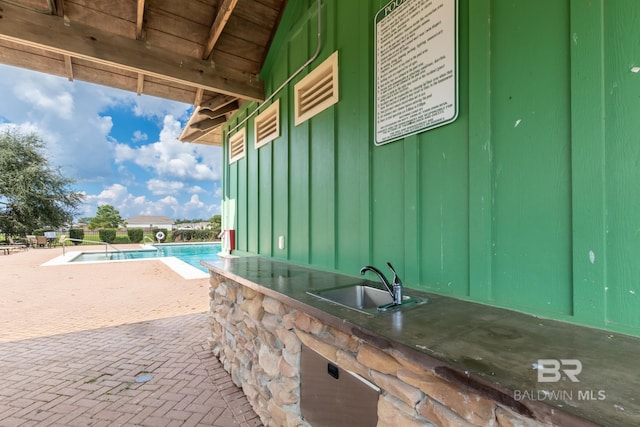 view of patio with area for grilling, sink, and a community pool