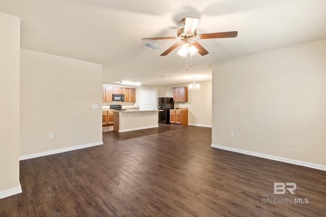 unfurnished living room with ceiling fan with notable chandelier and dark hardwood / wood-style flooring