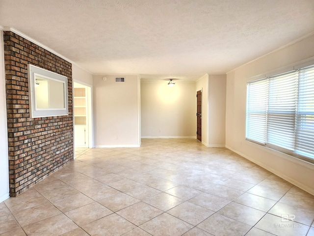 unfurnished room with ornamental molding, brick wall, a textured ceiling, and light tile patterned floors