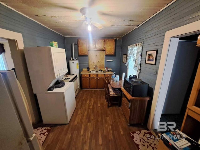kitchen with a sink, dark wood-style floors, wooden walls, light countertops, and freestanding refrigerator