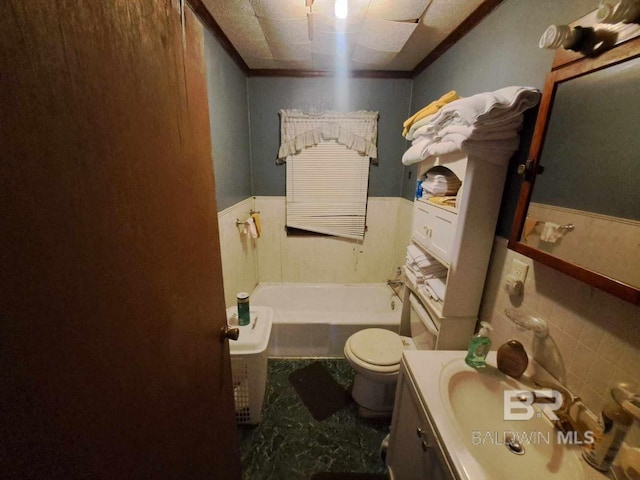 full bathroom with a wainscoted wall, a bath, toilet, vanity, and ornamental molding