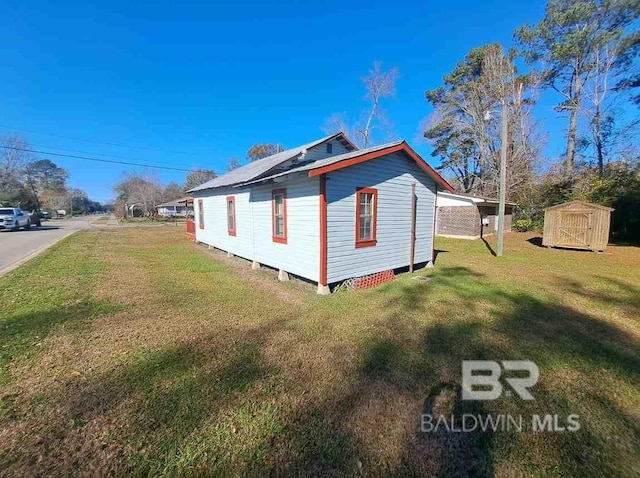 view of property exterior with a shed, a lawn, and an outbuilding