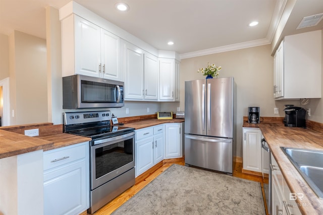 kitchen featuring appliances with stainless steel finishes, butcher block counters, visible vents, and white cabinets