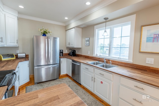 kitchen featuring butcher block countertops, white cabinetry, stainless steel appliances, and a sink