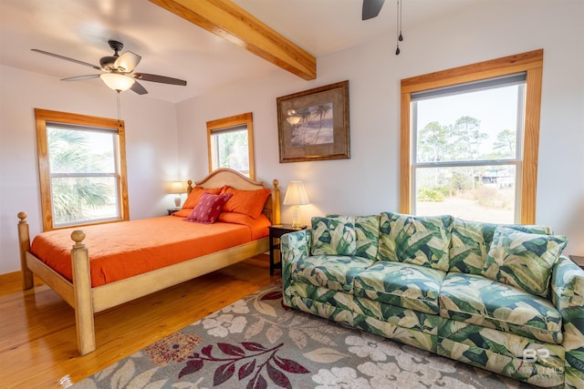 bedroom with ceiling fan, wood finished floors, and beam ceiling