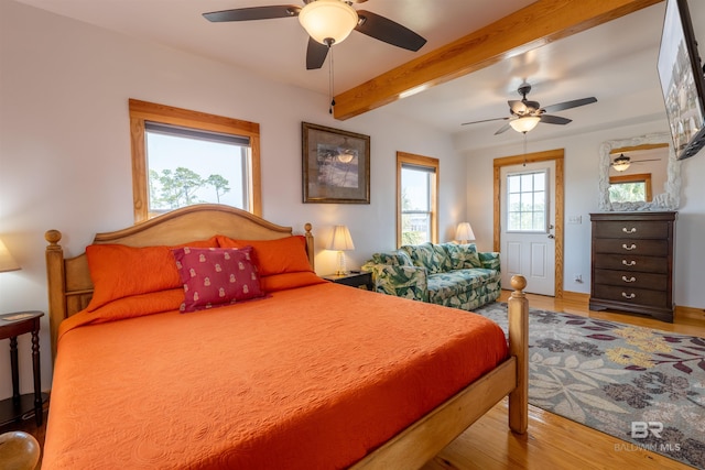 bedroom with ceiling fan, beamed ceiling, and wood finished floors