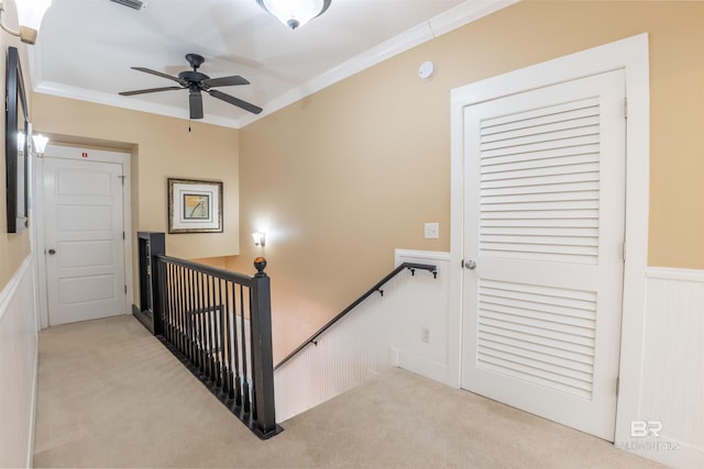 stairs with a wainscoted wall, crown molding, visible vents, and carpet flooring