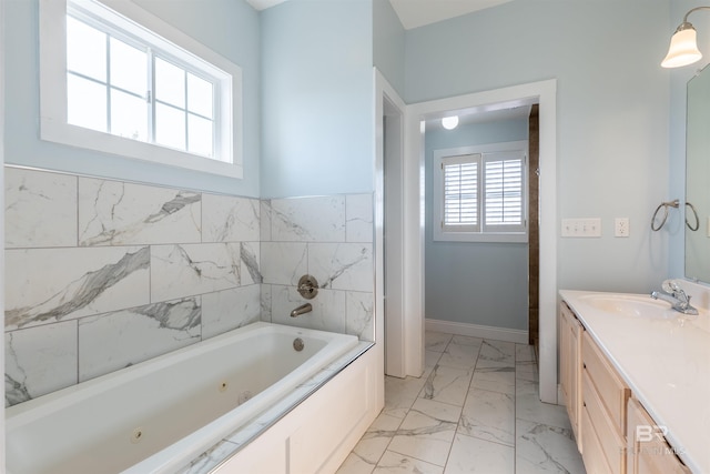 bathroom with a jetted tub, marble finish floor, and vanity