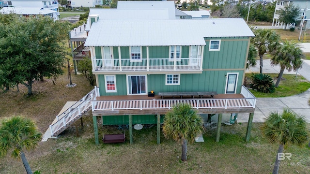 rear view of property with stairs, board and batten siding, and a balcony