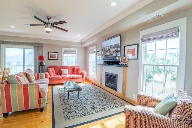 living area featuring crown molding, a fireplace, recessed lighting, visible vents, and light wood-type flooring