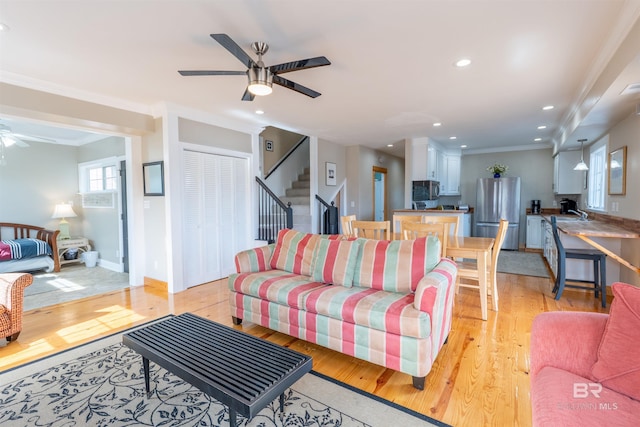 living area with light wood finished floors, ceiling fan, stairs, crown molding, and recessed lighting